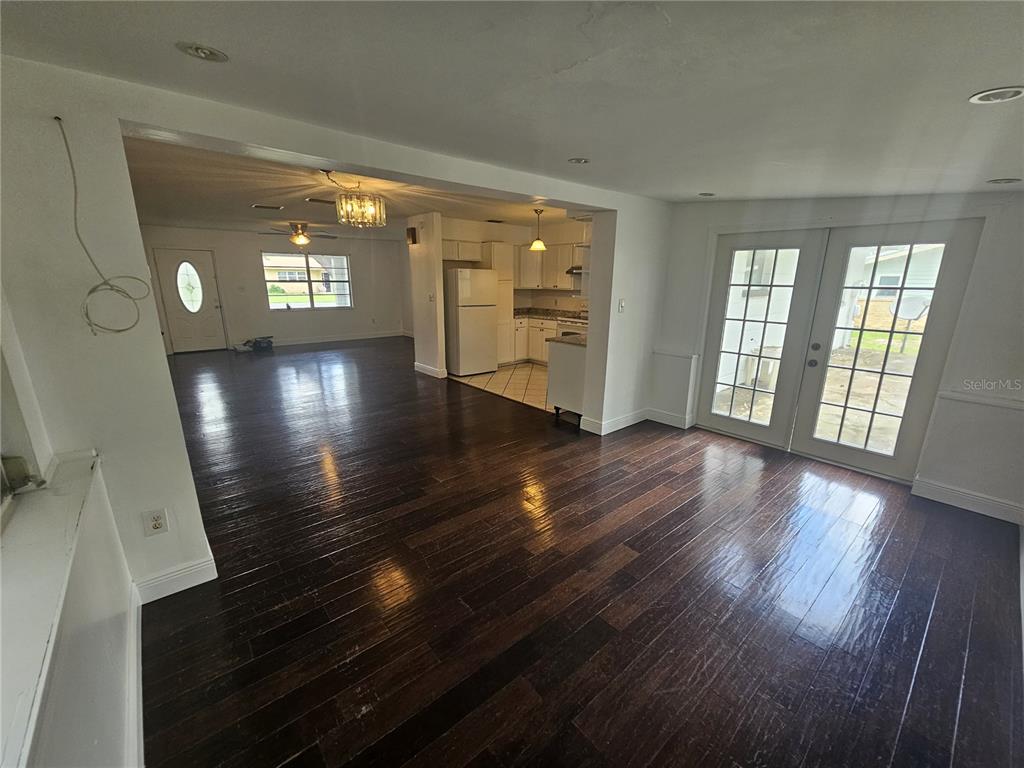 An open-concept living area with dark wood flooring, a kitchen, and French doors — 26 LAKE COURT LOOP, OCALA, FL