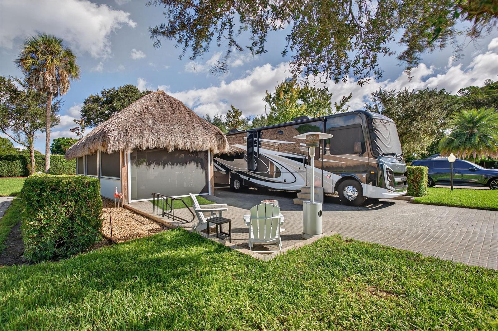 A large RV is parked on a paved lot next to a thatched-roof tiki hut — 161 N Cortez Drive # 161, Margate FL 33068, MARGATE, FL