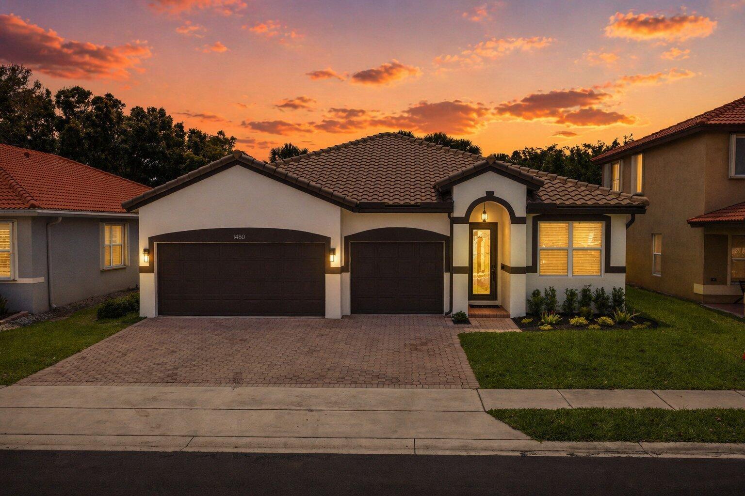A single-story house with a two-car garage and a tiled roof at sunset — 1480 Artimino Lane, Boynton Beach FL 33436, BOYNTON BEACH, FL