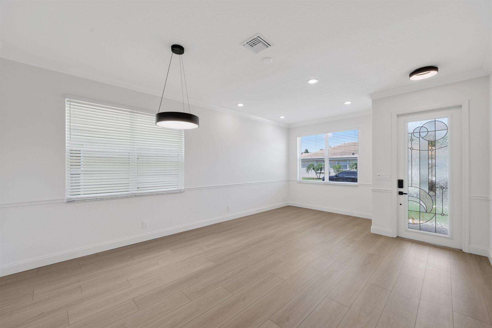 An empty room features light wood flooring, white walls with chair rail molding, and a pendant light — 1480 Artimino Lane, Boynton Beach FL 33436, BOYNTON BEACH, FL