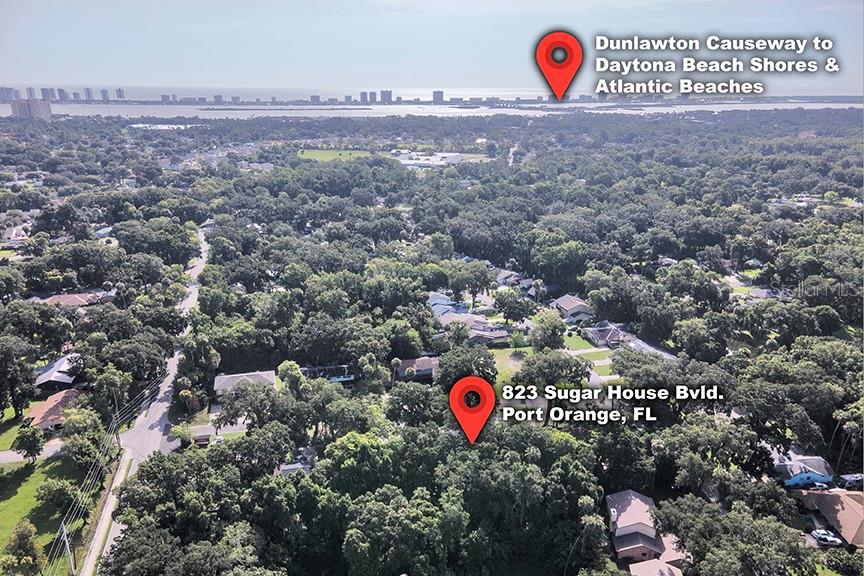 This aerial view shows a wooded residential neighborhood with a distant coastal skyline — 823 SUGAR HOUSE BOULEVARD, PORT ORANGE, FL