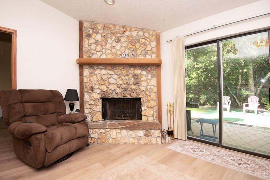 A living room features a stone fireplace, a brown recliner, and sliding glass doors — 823 SUGAR HOUSE BOULEVARD, PORT ORANGE, FL