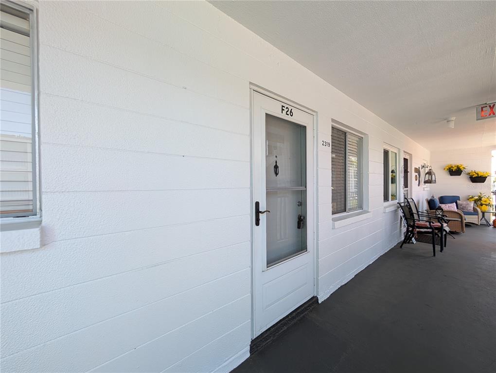 A white exterior wall features a front door labeled F26 and a covered walkway — 2319 CANAL DRIVE UNIT F26, BRADENTON, FL
