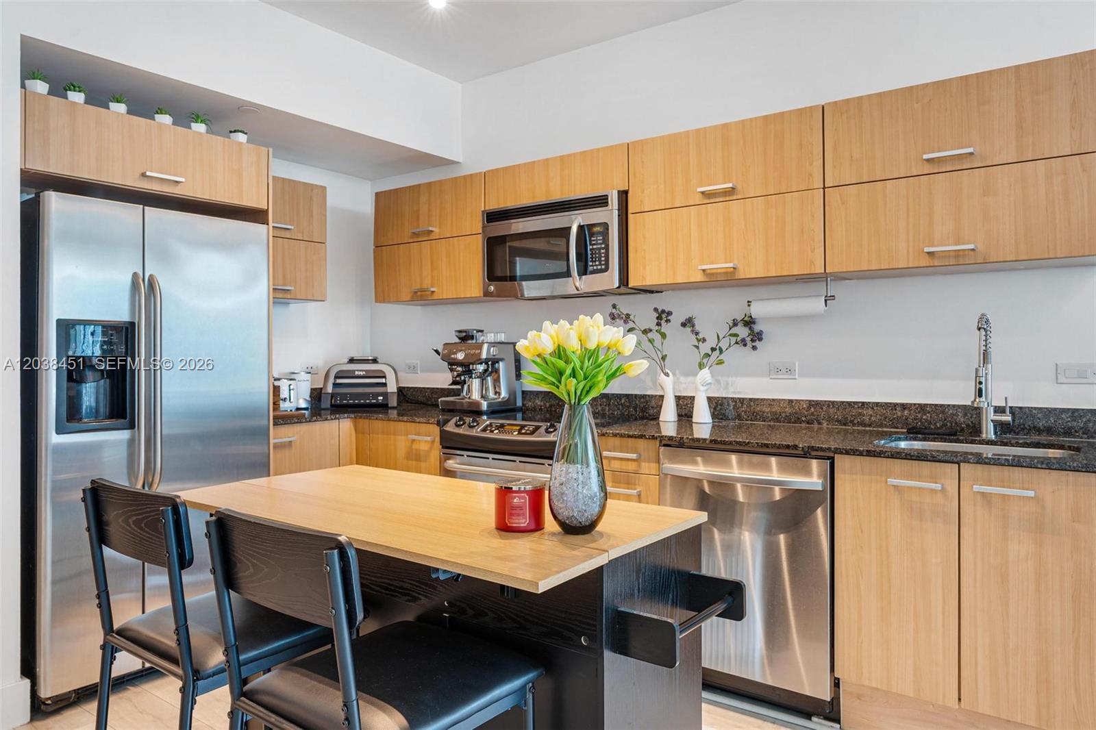A kitchen features light wood cabinets, stainless steel appliances, a dark countertop, and a small island — 350 S Miami Ave # 2108, Miami FL 33130, MIAMI, FL