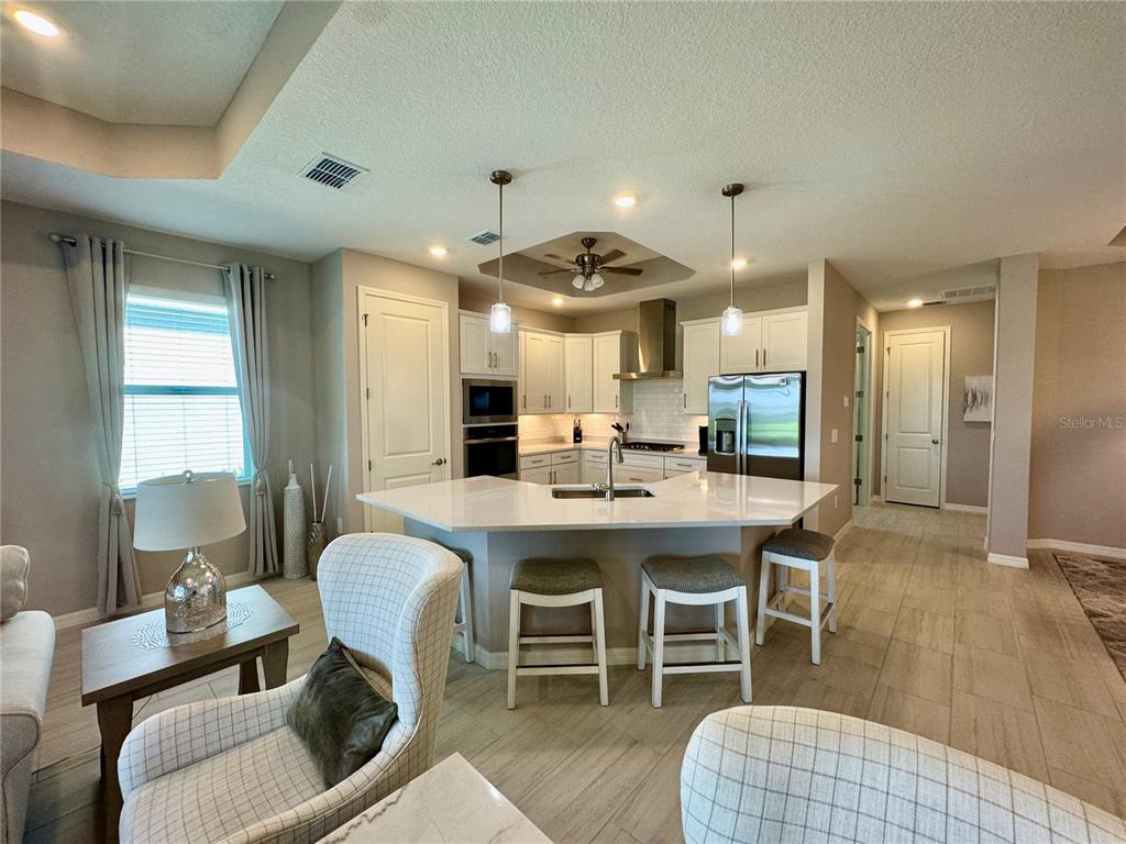 A kitchen with a white quartz island, stainless steel appliances, and light-colored tile flooring — 19140 CHERRYSTONE WAY, LAKEWOOD RANCH, FL