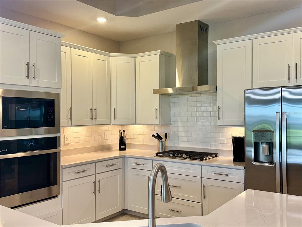 A kitchen features white cabinets, stainless steel appliances, a subway tile backsplash, and quartz countertops — 19140 CHERRYSTONE WAY, LAKEWOOD RANCH, FL