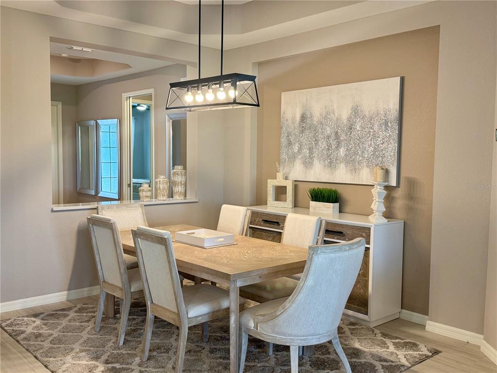 A dining room features a wooden table, upholstered chairs, a sideboard, and a pendant light — 19140 CHERRYSTONE WAY, LAKEWOOD RANCH, FL