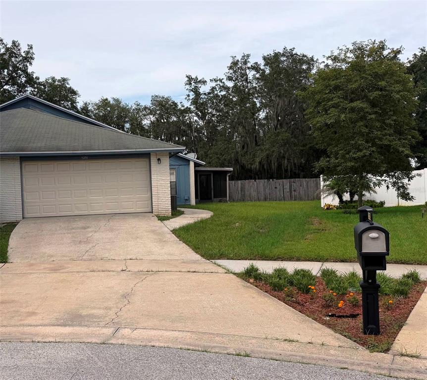 A single-story house with a two-car garage, a concrete driveway, and a front yard mailbox — 5291 INDIAN LAUREL COURT, ORLANDO, FL