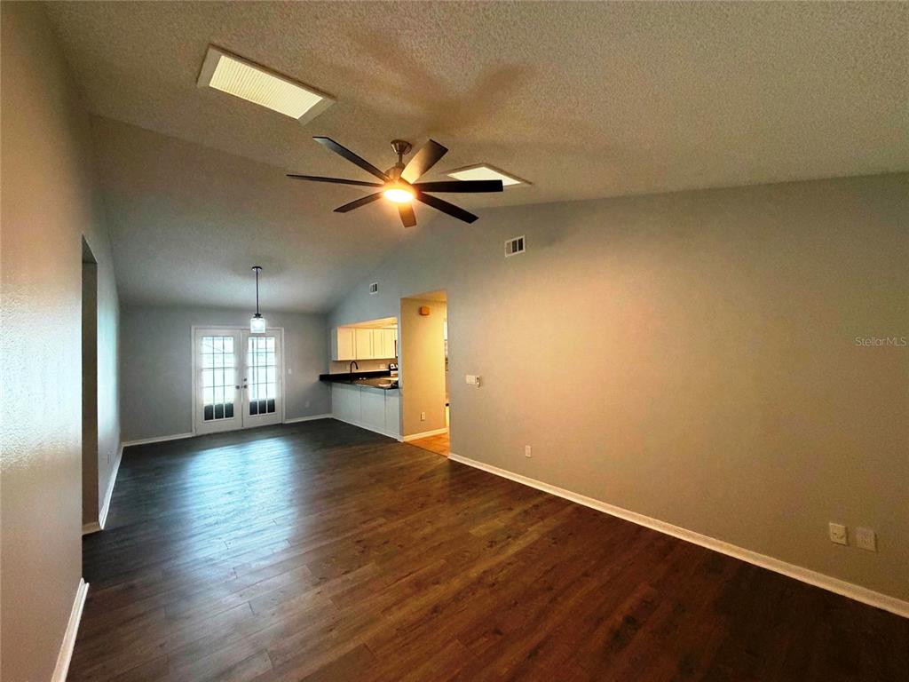 An open-concept living area features vaulted ceilings, dark wood-look flooring, and a ceiling fan — 5291 INDIAN LAUREL COURT, ORLANDO, FL