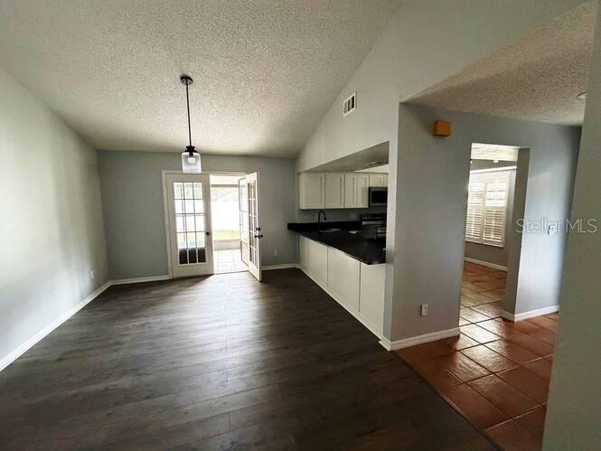 An open-concept living area features dark wood-look flooring, a vaulted ceiling, and a kitchen pass-through — 5291 INDIAN LAUREL COURT, ORLANDO, FL