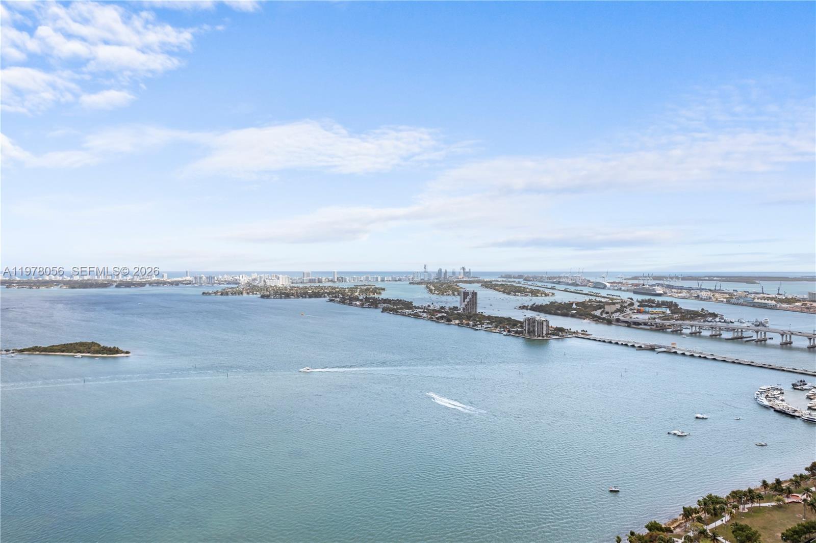 An aerial view shows a bay with islands, a bridge, and a distant city skyline — 2020 N Bayshore Dr # 4702, Miami FL 33137, MIAMI, FL