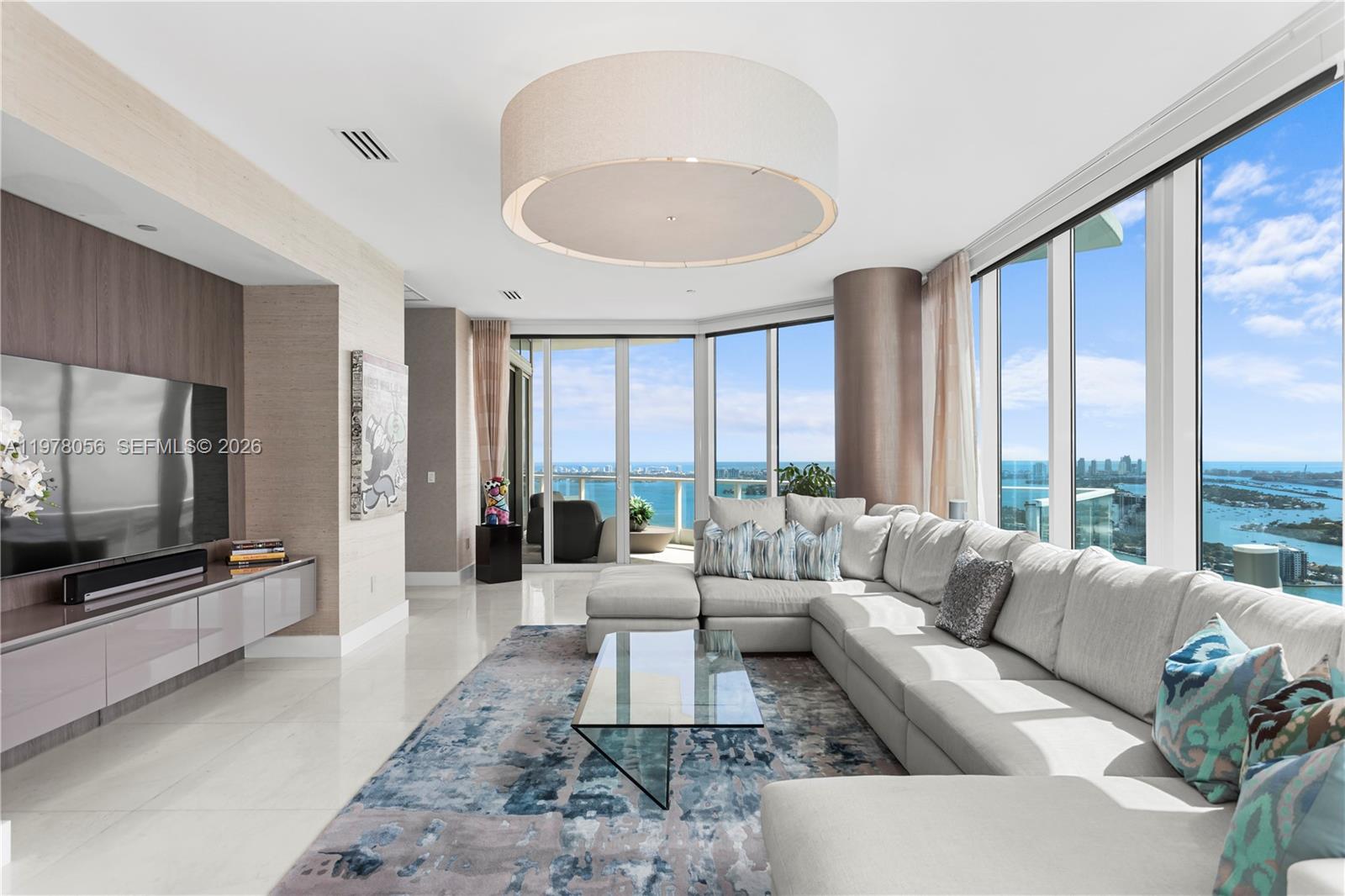 A modern living room features a large sectional sofa, glass coffee table, and floor-to-ceiling windows — 2020 N Bayshore Dr # 4702, Miami FL 33137, MIAMI, FL