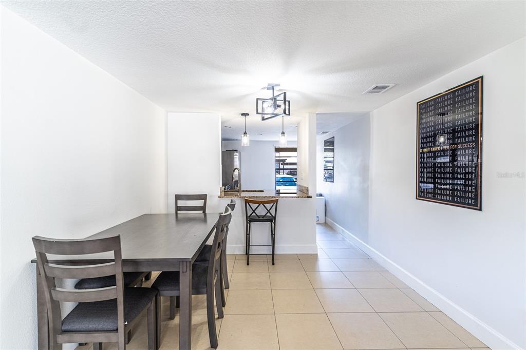 A dining area with a table, chairs, and a breakfast bar overlooking a kitchen — 4837 PURITAN CIRCLE UNIT #2505, TAMPA, FL
