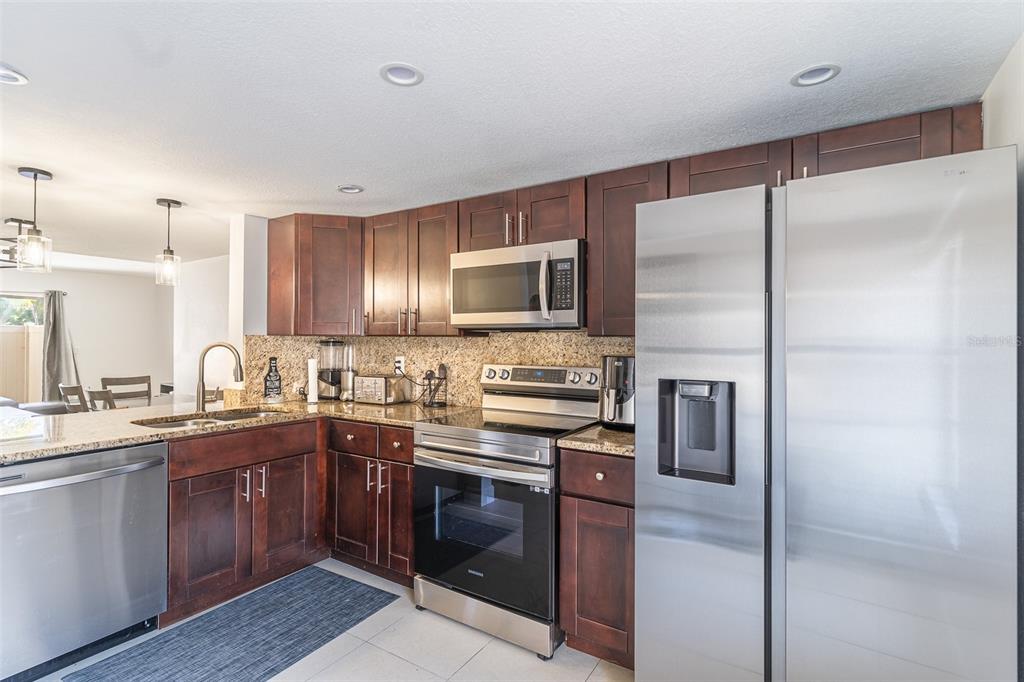 A kitchen with dark wood cabinets, stainless steel appliances, and granite countertops — 4837 PURITAN CIRCLE UNIT #2505, TAMPA, FL