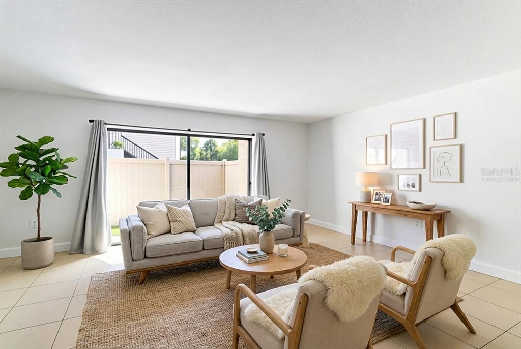 A living room features a gray sofa, two armchairs, a round coffee table, and sliding doors — 4837 PURITAN CIRCLE UNIT #2505, TAMPA, FL