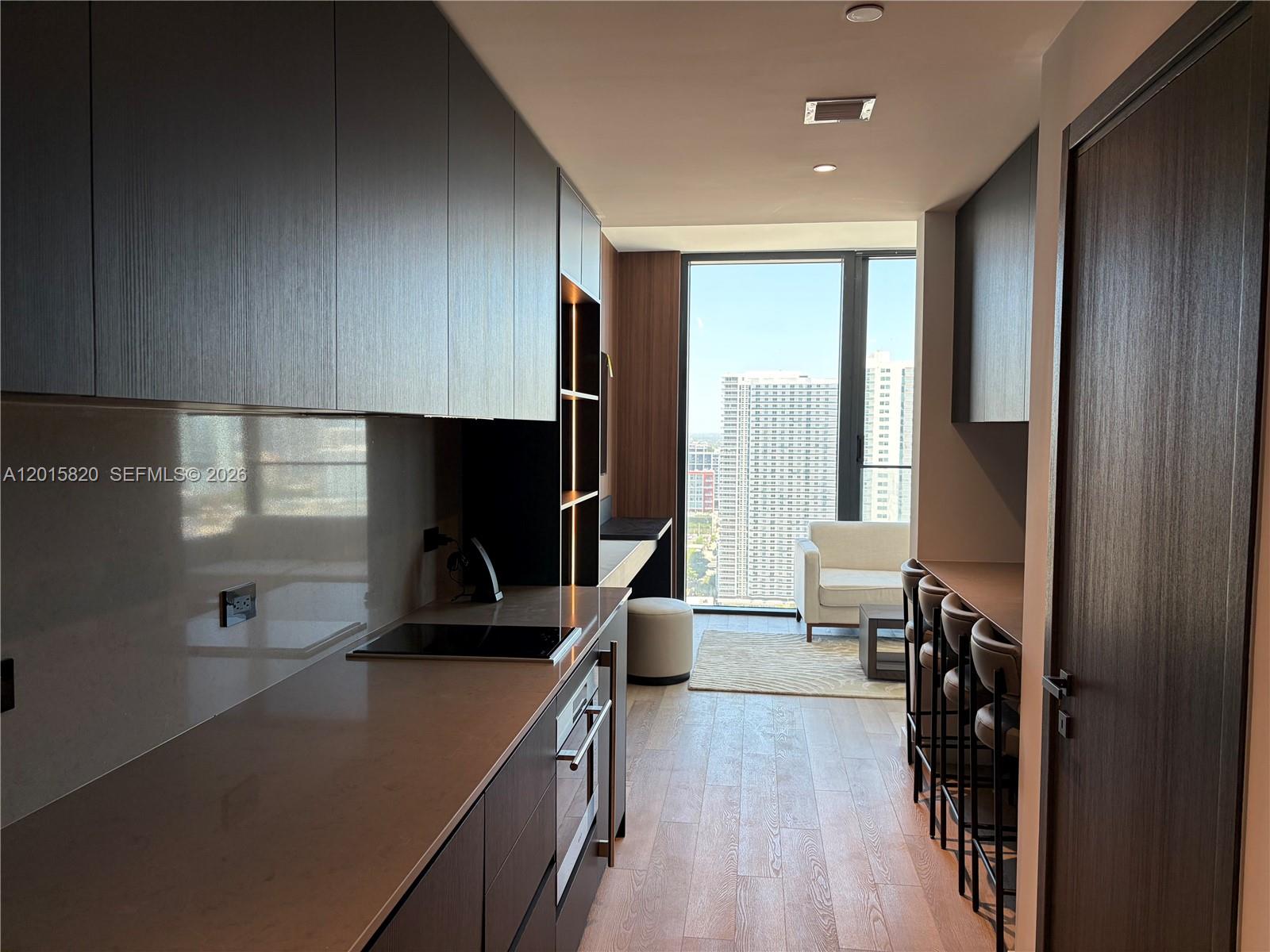 A modern kitchen features dark wood cabinetry, a breakfast bar, and floor-to-ceiling windows — 20 ne 11th st # 2805, Miami FL 33132, MIAMI, FL
