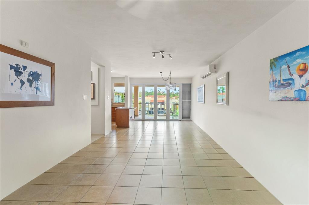 A tiled living area leads to a balcony through glass doors with a kitchen visible — 180 PALMAS DRIVE UNIT 9C, HUMACAO, PR