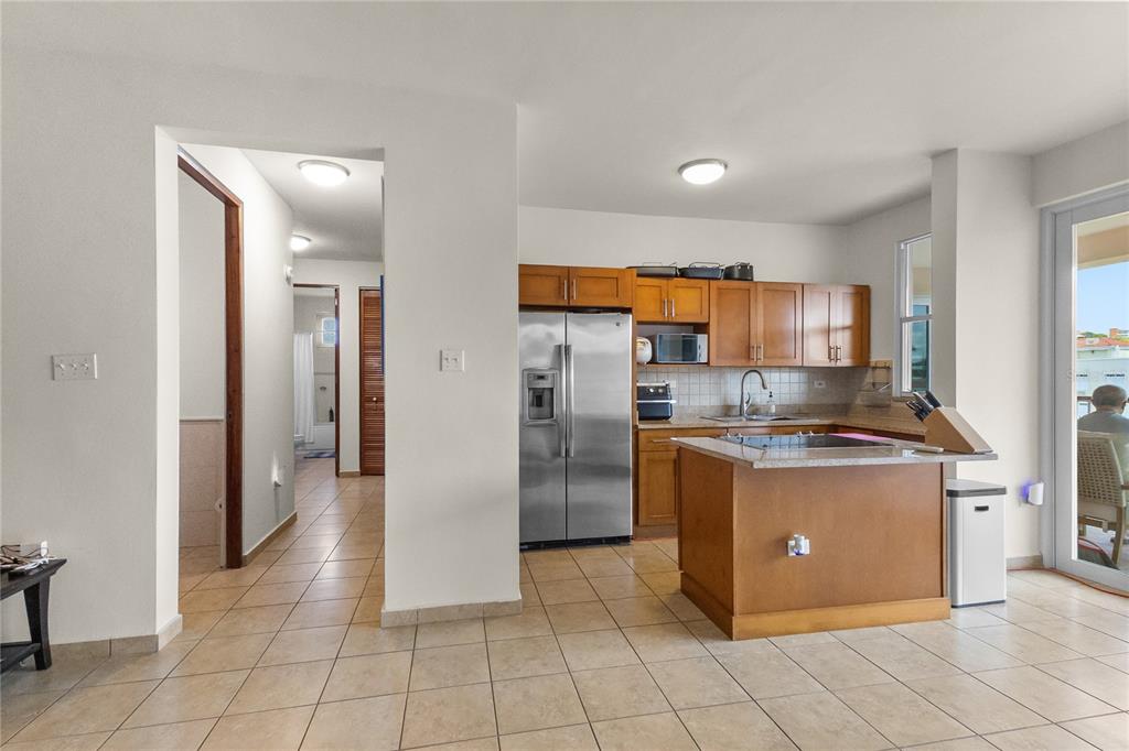 A kitchen features wooden cabinets, stainless steel appliances, a center island, and tiled flooring — 180 PALMAS DRIVE UNIT 9C, HUMACAO, PR