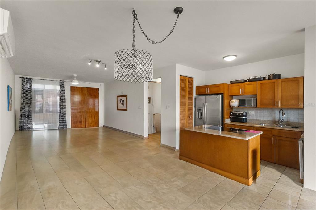 An open-concept kitchen and living area with tile flooring, wood cabinets, and a crystal chandelier — 180 PALMAS DRIVE UNIT 9C, HUMACAO, PR
