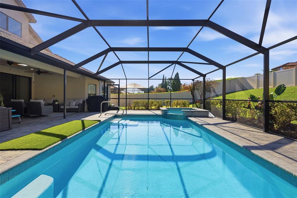 A swimming pool and spa are enclosed within a screened lanai next to a patio — 1844 VIA LAGO DRIVE, LAKELAND, FL