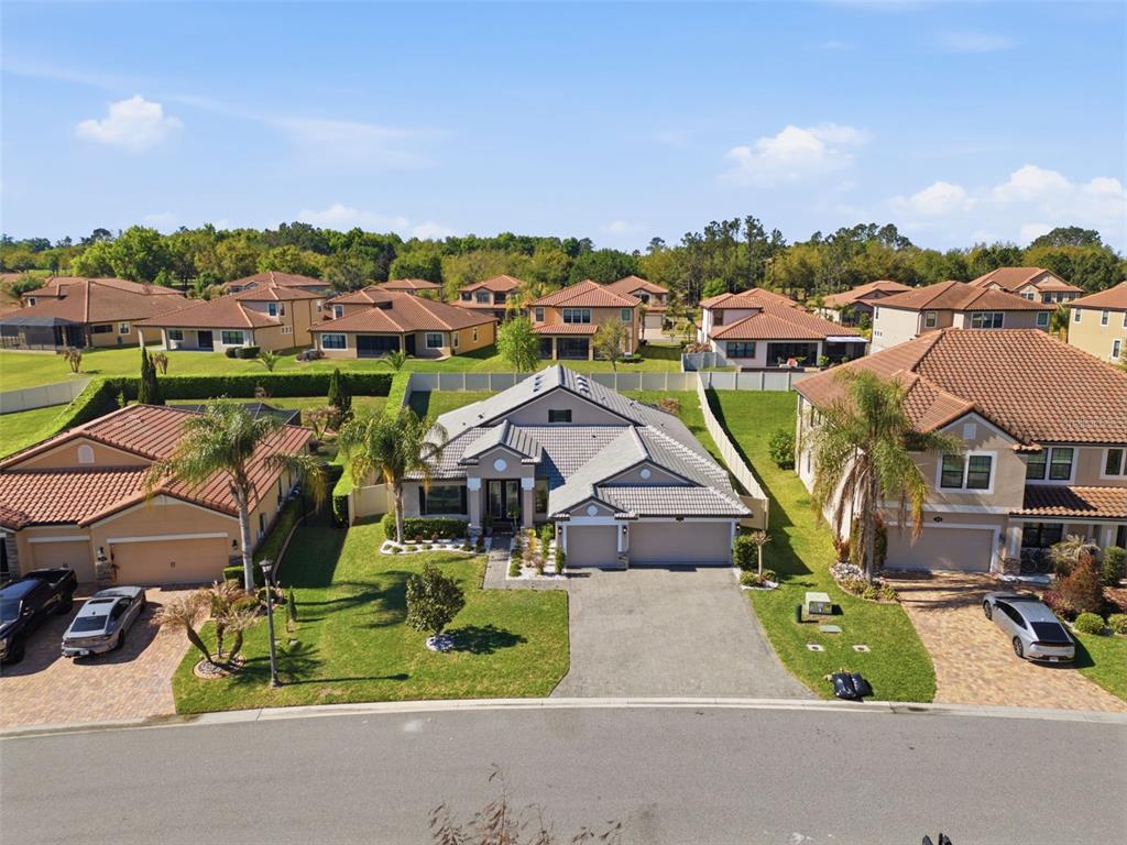 An aerial view of a suburban neighborhood featuring several single-family homes with tiled roofs — 1844 VIA LAGO DRIVE, LAKELAND, FL