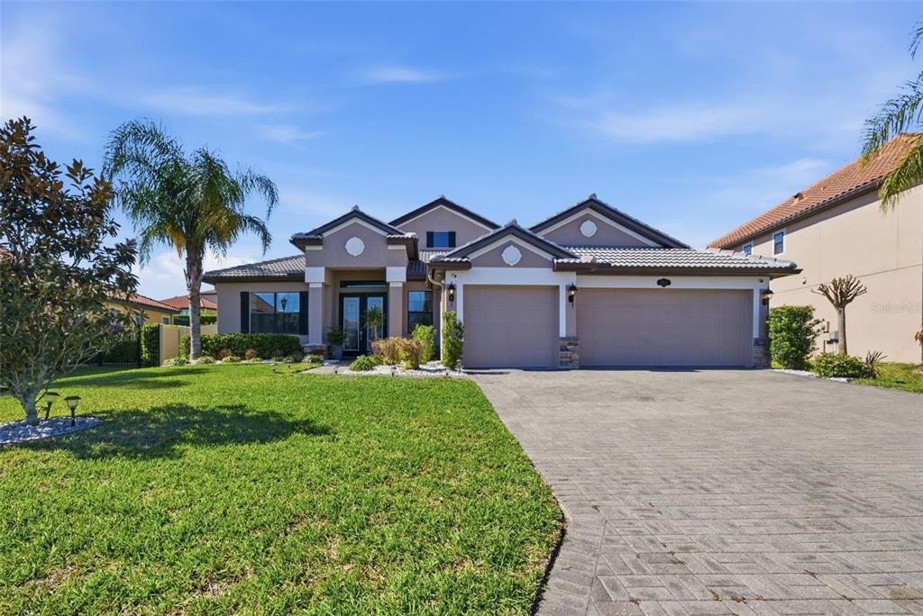 A single-story house with a beige exterior, a paved driveway, and a manicured front lawn — 1844 VIA LAGO DRIVE, LAKELAND, FL
