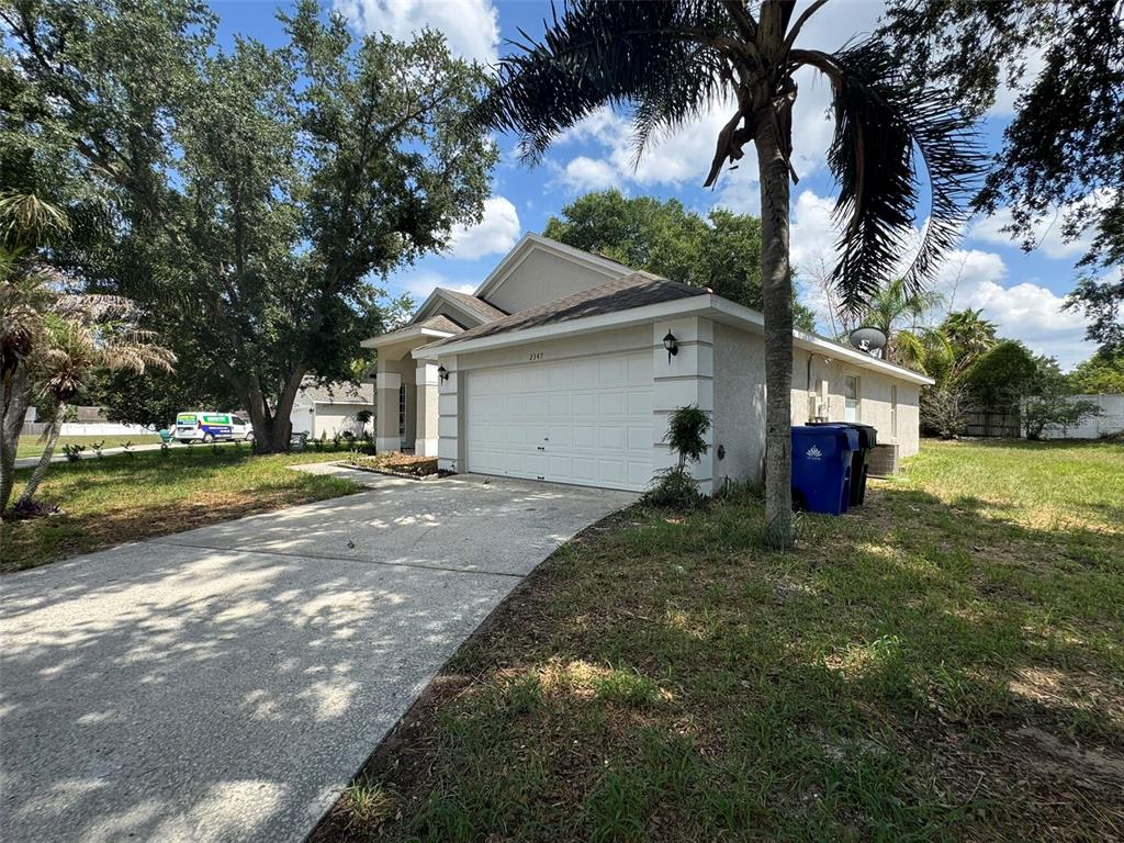 A single-story house with a white garage door, concrete driveway, and a palm tree — 2347 BLAKE WAY, OCOEE, FL