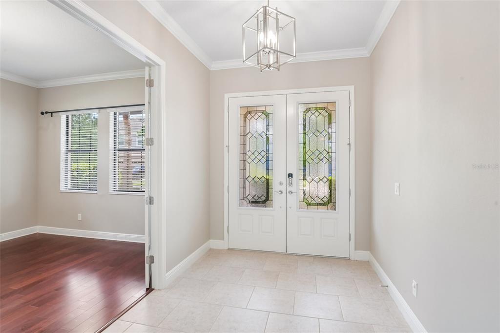 An entryway features a tiled floor, a geometric chandelier, and double doors with decorative glass — 8355 SWISS CHARD CIRCLE, LAND O LAKES, FL