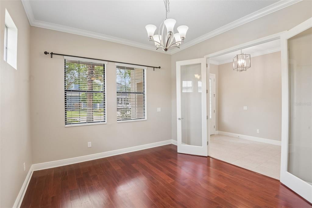 An empty room with hardwood floors, a chandelier, and glass French doors leading to another room — 8355 SWISS CHARD CIRCLE, LAND O LAKES, FL