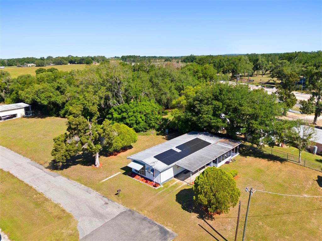 An aerial view shows a single-story house with solar panels on a large, grassy lot — 10220 WELLINGTON AVENUE, DADE CITY, FL