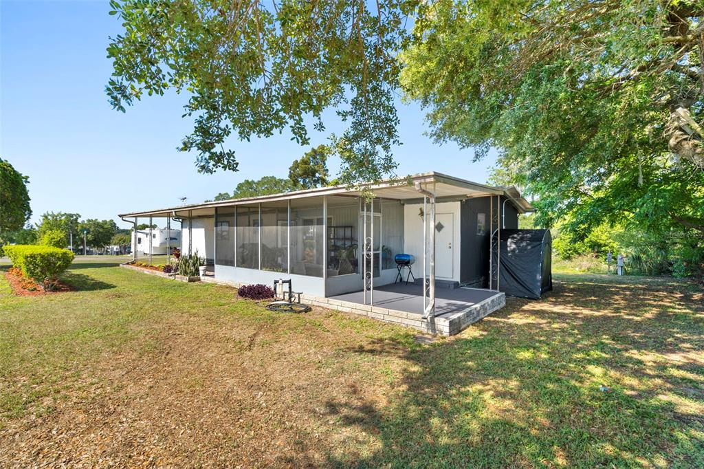 A mobile home with a screened-in porch and an attached open patio under a metal roof — 10220 WELLINGTON AVENUE, DADE CITY, FL