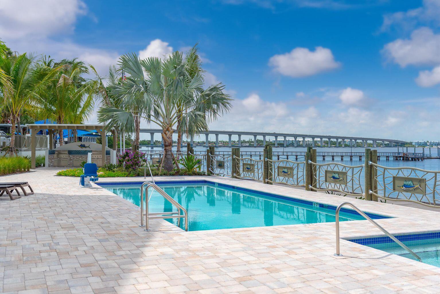 A swimming pool with a paved deck overlooks a bay and a long bridge — 41 SW Seminole Street # 410, Stuart FL 34994, STUART, FL