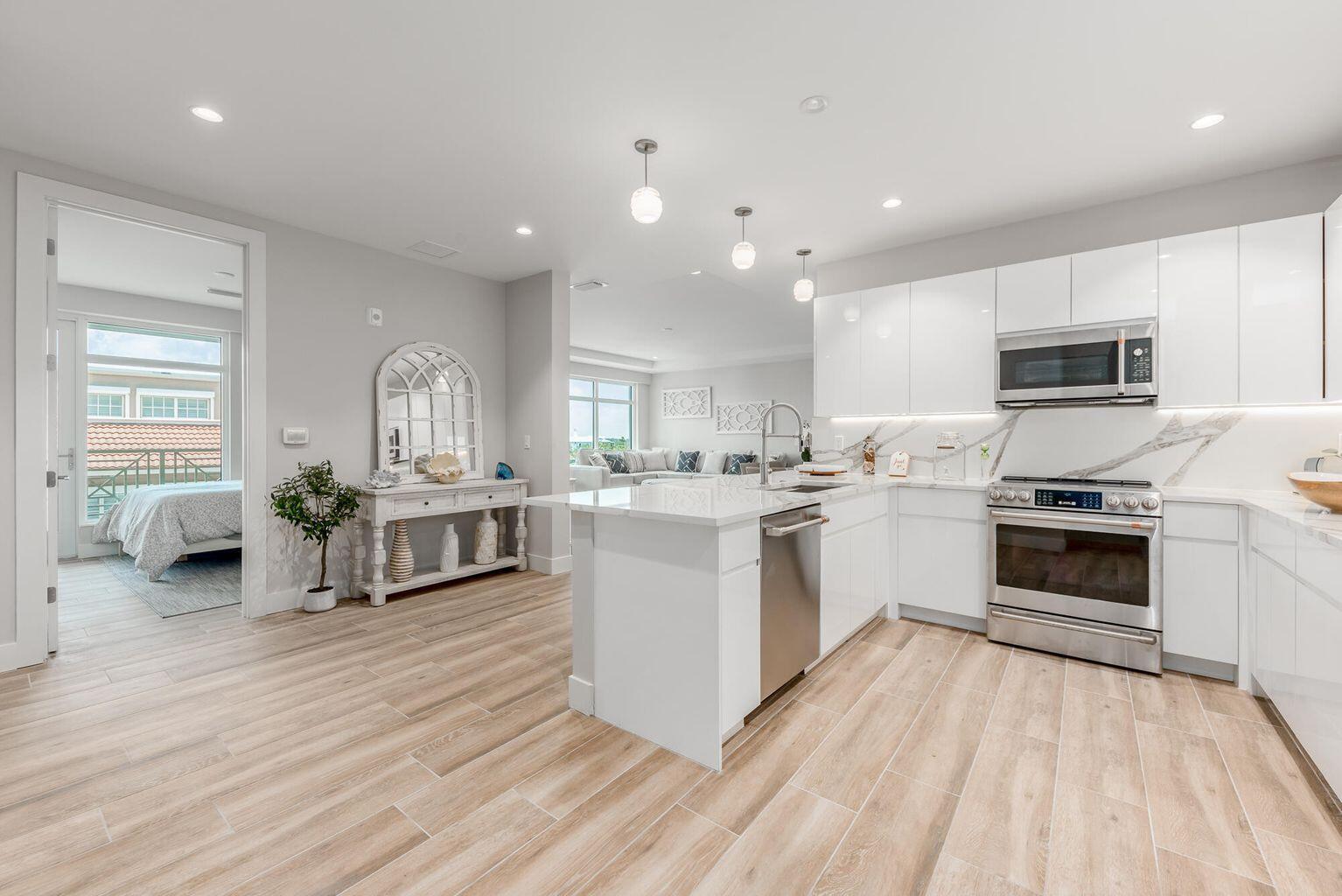 A modern kitchen with white cabinets, stainless steel appliances, and an island, adjacent to a bedroom — 41 SW Seminole Street # 410, Stuart FL 34994, STUART, FL