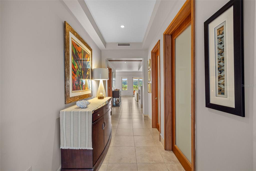 A hallway with tile flooring, a wooden console table, and framed artwork on the walls — 500 PLANTATION VILLAGE DRIVE UNIT 1201, DORADO, PR