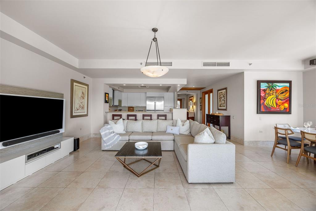 A living room with a large sectional sofa, coffee table, television, and open kitchen area — 500 PLANTATION VILLAGE DRIVE UNIT 1201, DORADO, PR