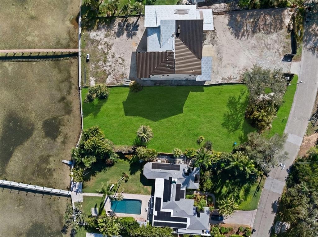 An aerial view shows two waterfront properties with a large shared lawn and private docks — 6100 BAHAMA SHORES DRIVE S, ST PETERSBURG, FL