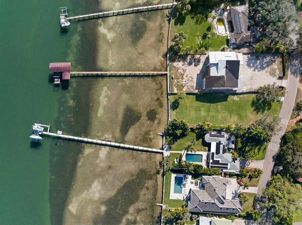 An aerial view shows three waterfront homes with long private docks extending into the water — 6100 BAHAMA SHORES DRIVE S, ST PETERSBURG, FL