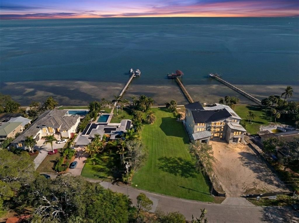 An aerial view shows two waterfront houses with private docks and a large grassy lot — 6100 BAHAMA SHORES DRIVE S, ST PETERSBURG, FL