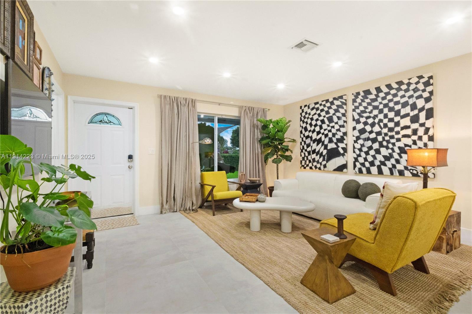 A living room features a white sofa, two yellow armchairs, and large black-and-white wall art — 191 SE 13th Ave, Pompano Beach FL 33060, POMPANO BEACH, FL