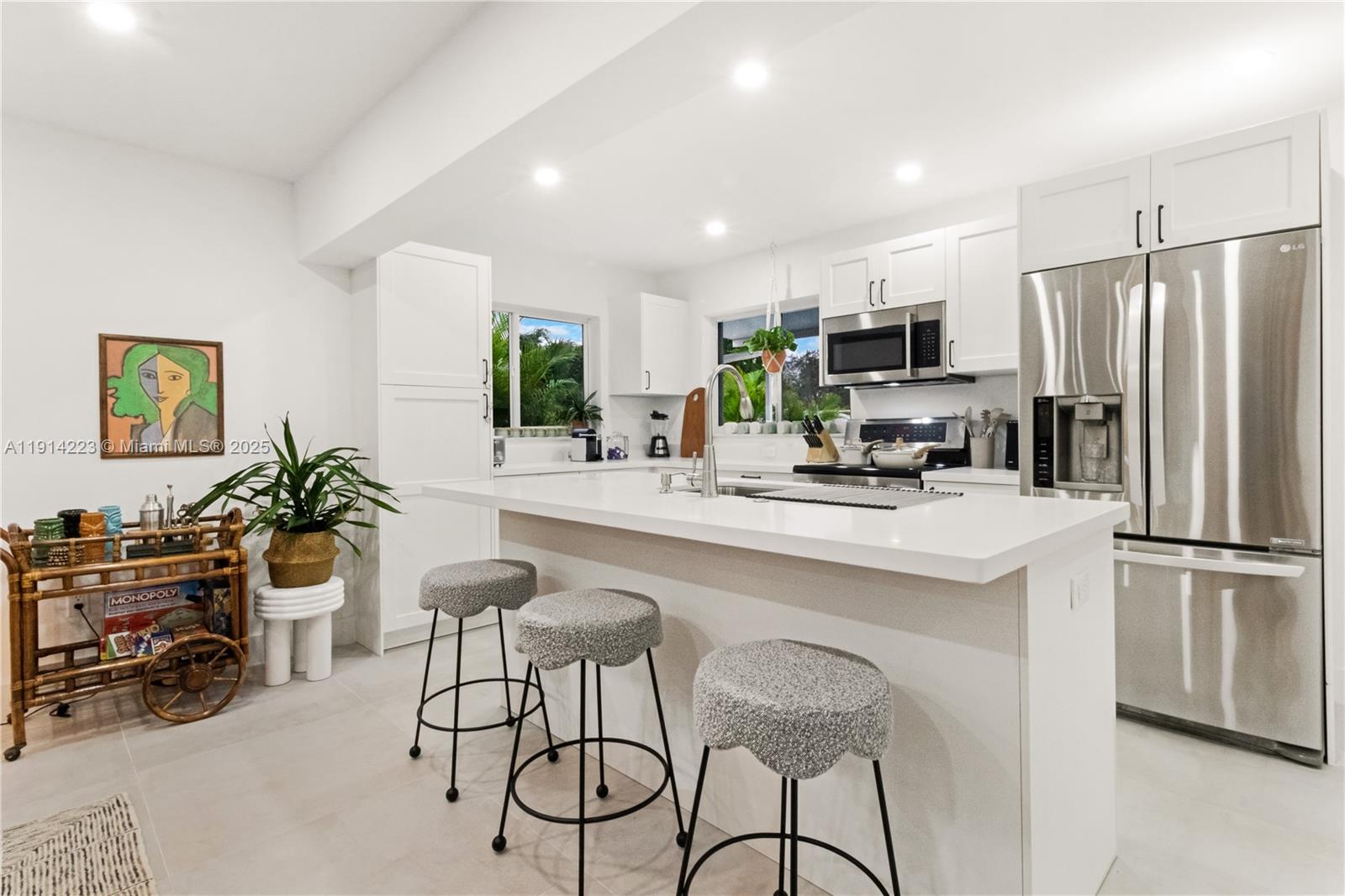 A modern kitchen features white cabinetry, a quartz-topped island with stools, and stainless steel appliances — 191 SE 13th Ave, Pompano Beach FL 33060, POMPANO BEACH, FL