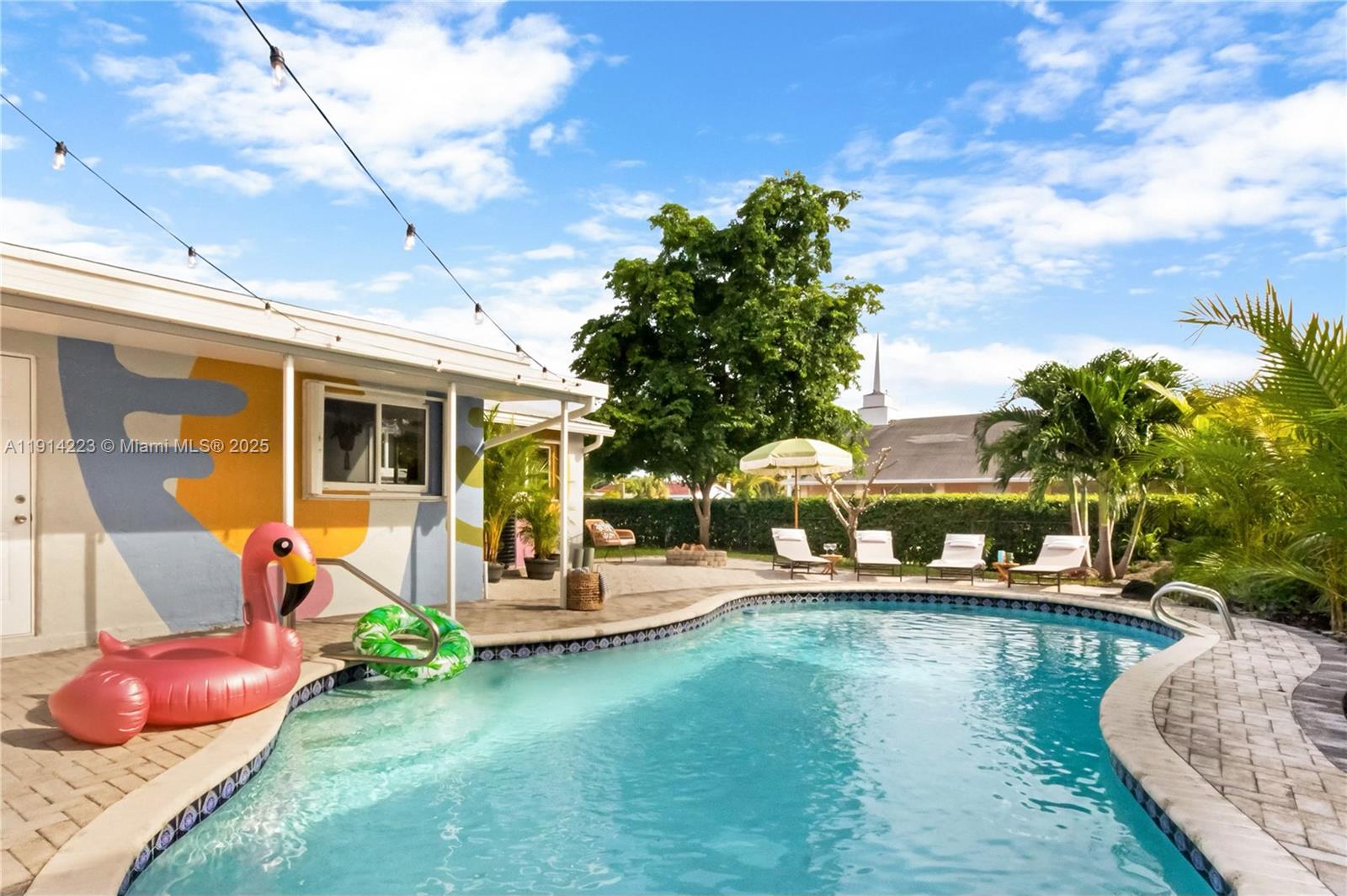 A swimming pool with a flamingo float sits beside a house with a painted mural — 191 SE 13th Ave, Pompano Beach FL 33060, POMPANO BEACH, FL