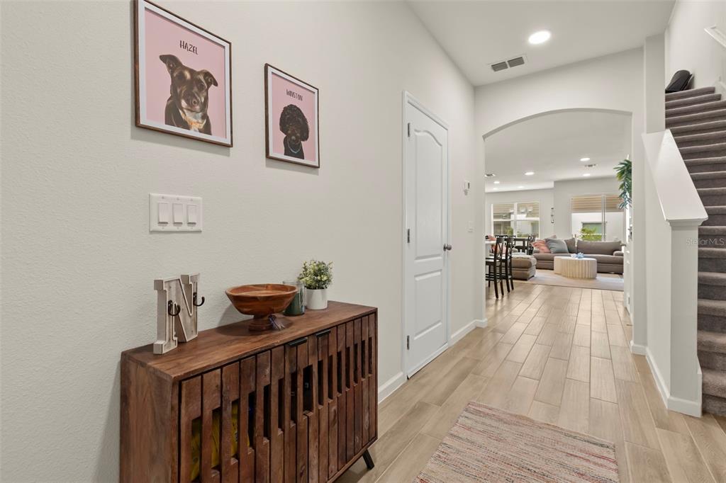 A hallway features a wooden console table, framed pet portraits, and a staircase — 3040 PILOT HOUSE PLACE, OVIEDO, FL