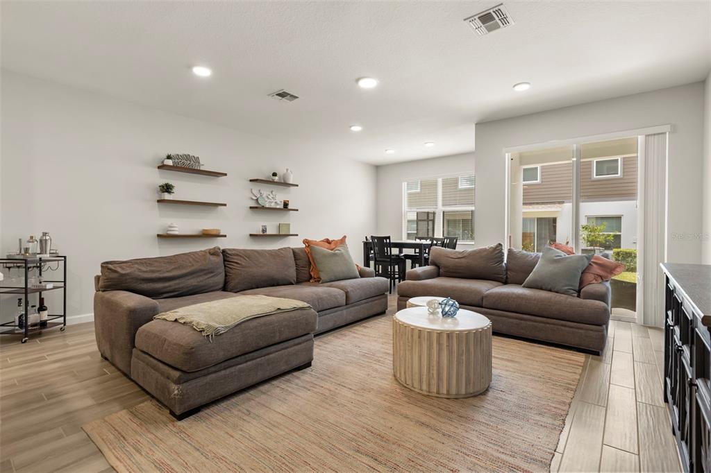 A living room with a sectional sofa, coffee table, and open dining area — 3040 PILOT HOUSE PLACE, OVIEDO, FL