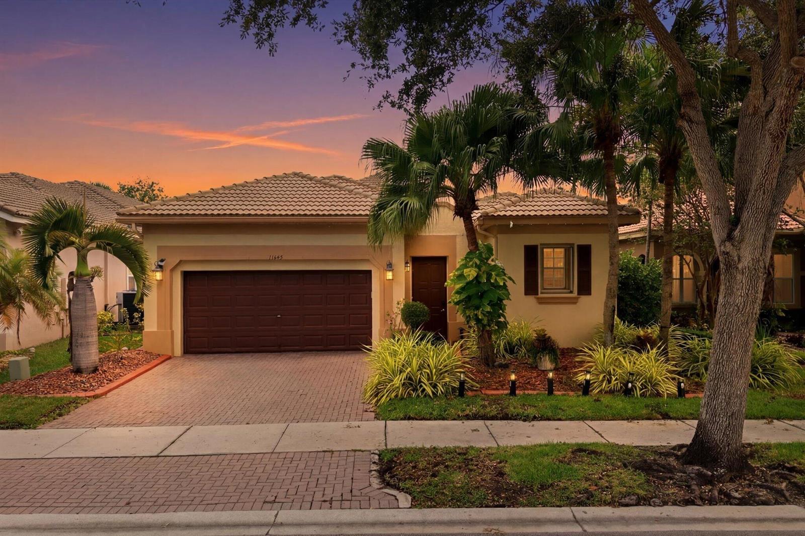 A kitchen with light wood cabinets, a breakfast bar with four stools, and tile flooring — 11645 NW 71st Place, Parkland FL 33076, PARKLAND, FL