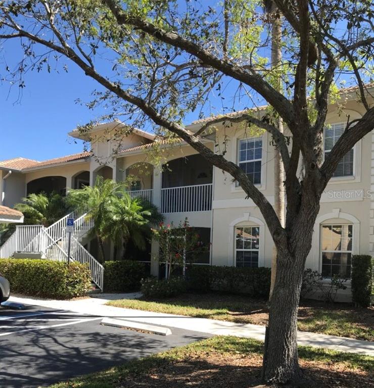 A two-story apartment building with a staircase, screened balconies, and a large tree in front — 3104 L PAVIA BOULEVARD UNIT 3104, VENICE, FL