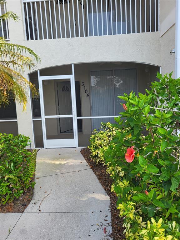A ground-level apartment entrance features a screened porch, a white door, and a concrete walkway — 3104 L PAVIA BOULEVARD UNIT 3104, VENICE, FL