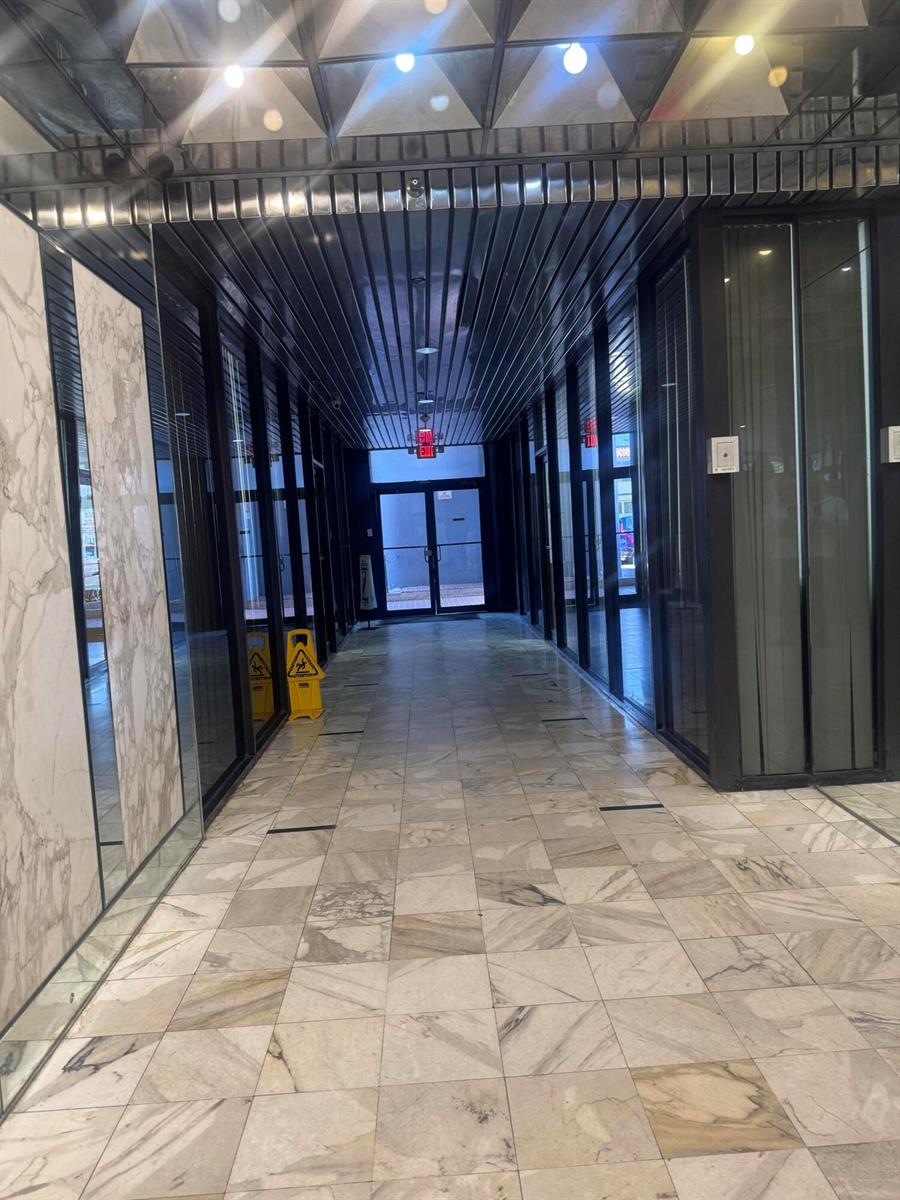 A hallway with marble tile flooring, glass-paneled walls, and a metallic slatted ceiling — 330 SW 27th Avenue # 309, Miami FL 33135, MIAMI, FL