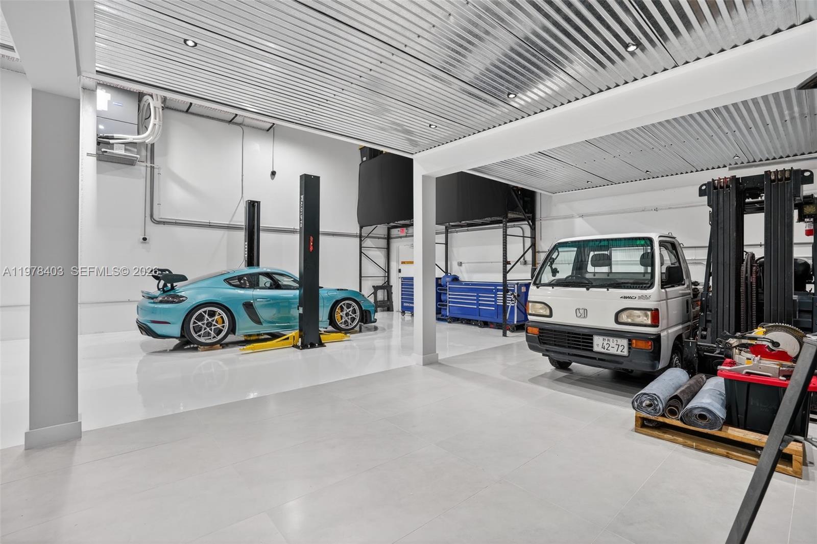 A spacious, modern garage features a car lift, a sports car, and a small truck — 13500 SW 134th Ave # 4A, Miami FL 33186, MIAMI, FL