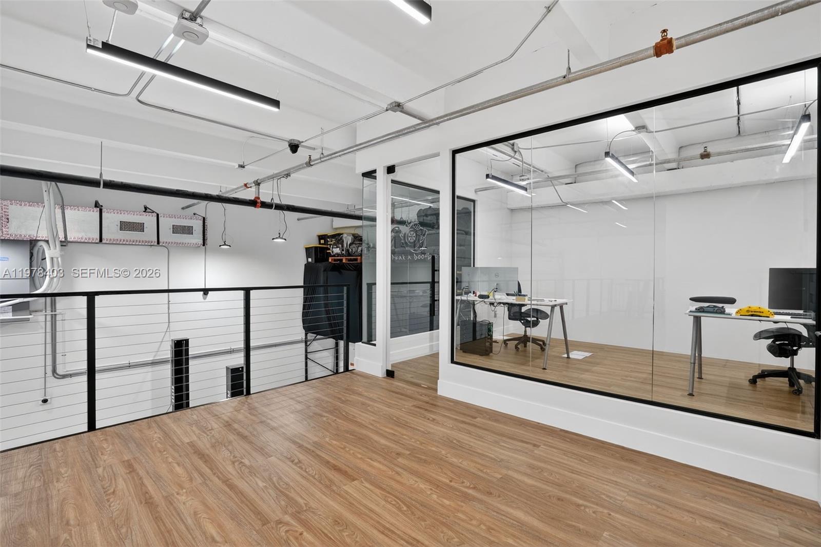 An office space features glass walls, wood-look flooring, and an open mezzanine overlooking a lower level — 13500 SW 134th Ave # 4A, Miami FL 33186, MIAMI, FL