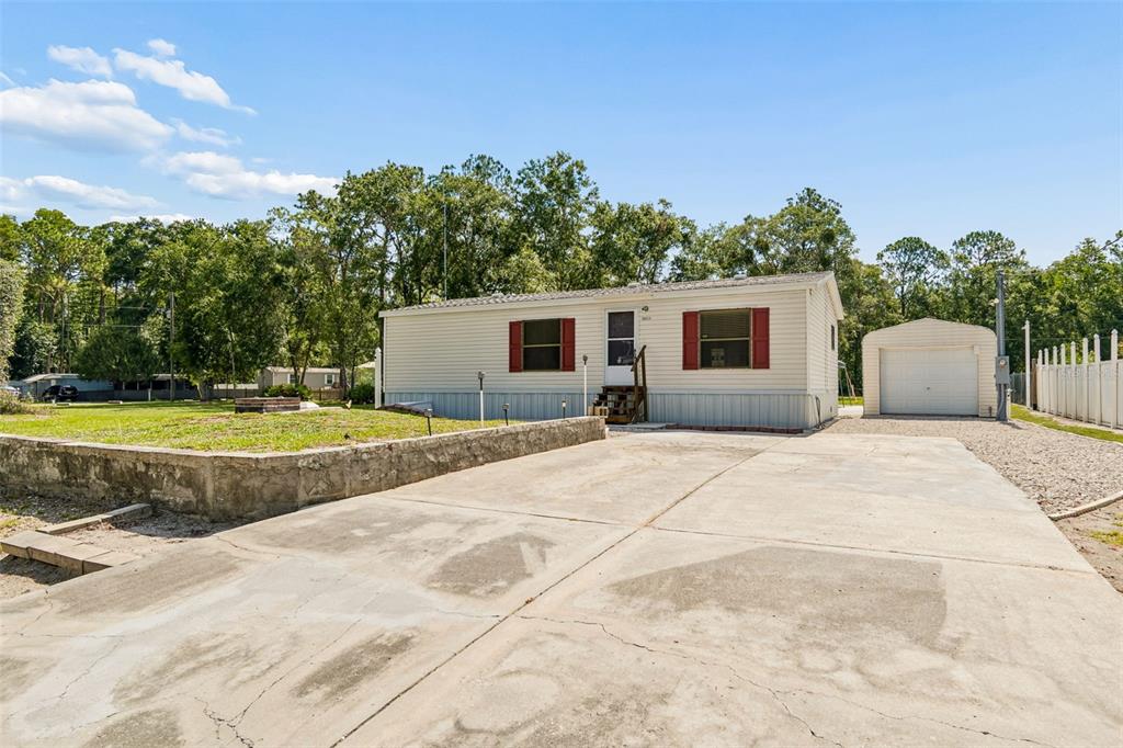 A single-story manufactured home with a concrete driveway, retaining wall, and detached garage — 10654 HOLGATE STREET, NEW PORT RICHEY, FL